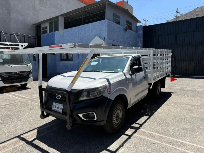 Pickup gris con carrocería especial de redilas y copete vista lateral izquierda