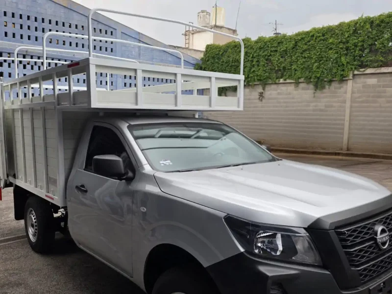 Camioneta pickup con caja de redilas y copete estacionada en patio exterior